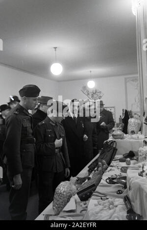 Besucher der Leipziger Frühjahrsmesse vor einem Stand mit Kunsthandwerk Deutschland ; 1941. Les visiteurs de la Leipziger Frühjahrsmesse devant un stand avec des illustrations ; Allemagne 1941. Banque D'Images