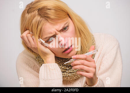 La fièvre de la pause des recours. La prise de température et d'évaluer les symptômes. Femme se sent gravement malade l'éternuement. Fille en tissu écharpe tenir thermomètre et close up. Mesures Banque D'Images