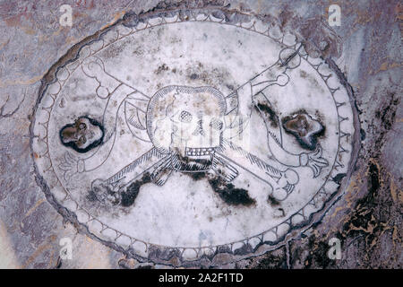 Vieux crâne avec les os croisés sculptés en pierre de marbre italien sur tombe. Crypte médiévale antique. Motif crâne décoratif, Memento mori. Pise Italie Banque D'Images