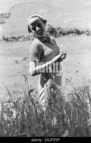 Eine junge Frau auf einer Wiese im Schwarzwald, Deutschland 1930er Jahre. Une jeune femme debout sur une prairie de la Forêt-Noire, Allemagne 1930. Banque D'Images