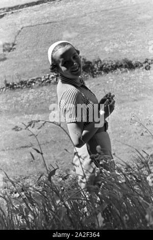 Eine junge Frau auf einer Wiese im Schwarzwald, Deutschland 1930er Jahre. Une jeune femme debout sur une prairie de la Forêt-Noire, Allemagne 1930. Banque D'Images