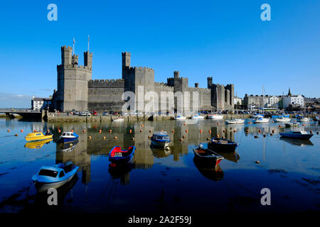 Vue sur la rivière Sieont vers château de Caernarfon sur un matin calme encore une réflexion sur l'eau à marée haute avec des bateaux amarrés au premier plan Banque D'Images
