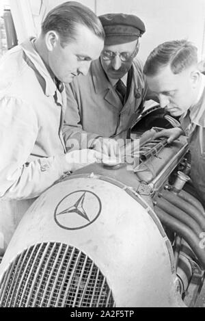 Hermann Lang dans Autorennfahrer der der Autowerkstatt im Gespräch mit Automechanikern, Deutschland 1930 er Jahre. Le pilote de course Hermann Lang parle de mécanique auto dans l'autoshop, Allemagne 1930. Banque D'Images