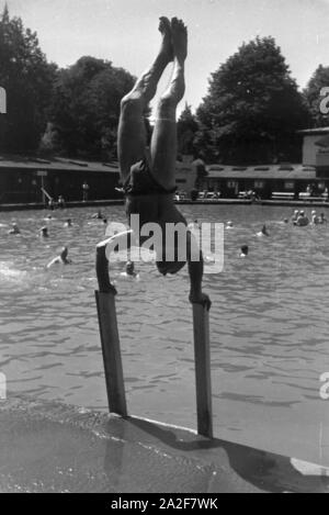 Akrobatischen Kunststücken Badegast Ein bei einem Stuttgarter Freibad, Deutschland 1930 er Jahre. Une place de l'extraction de prouesses acrobatiques dans une baignoire en plein air à Stuttgart, Allemagne 1930. Banque D'Images