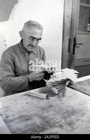 Ein Mitarbeiter in den Heller Kunst Werkstätten in der Eifel schleift ausgesägten Holzfiguren die Kanten der ab, Deutschland 1930 er Jahre. Un employé de la Heller Kunst des ateliers dans l'Eifel le meulage des bords de l'out figures en bois scié, Allemagne 1930. Banque D'Images