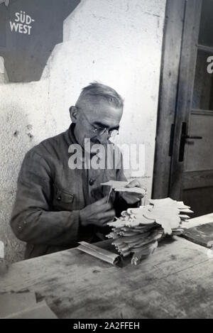 Ein Mitarbeiter in den Heller Kunst Werkstätten in der Eifel schleift ausgesägten Holzfiguren die Kanten der ab, Deutschland 1930 er Jahre. Un employé de la Heller Kunst des ateliers dans l'Eifel le meulage des bords de l'out figures en bois scié, Allemagne 1930. Banque D'Images