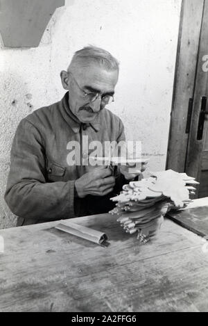 Ein Mitarbeiter in den Heller Kunst Werkstätten in der Eifel schleift ausgesägten Holzfiguren die Kanten der ab, Deutschland 1930 er Jahre. Un employé de la Heller Kunst des ateliers dans l'Eifel le meulage des bords de l'out figures en bois scié, Allemagne 1930. Banque D'Images