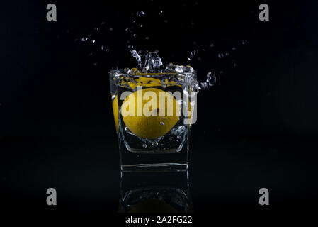 Splash frais citron en verre isolé sur fond noir Banque D'Images