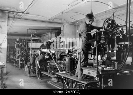 Druckereimitarbeiter bei der Arbeit an der Rotationsdruckmaschine Maschinenbaukonzerns in den Werken des MAN (Maschinenfabrik Augsburg-Nürnberg), Deutschland 1930 er Jahre. Les travailleurs de l'imprimerie sur la presse d'impression rotative dans les usines de la société d'ingénierie mécanique (homme), Maschinenfabrik Augsburg-Nürnberg Allemagne 1930. Banque D'Images