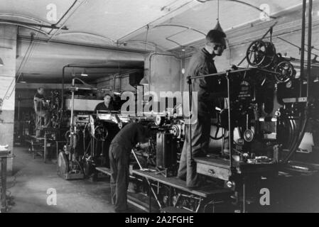 Druckereimitarbeiter bei der Arbeit an der Rotationsdruckmaschine Maschinenbaukonzerns in den Werken des MAN (Maschinenfabrik Augsburg-Nürnberg), Deutschland 1930 er Jahre. Les travailleurs de l'imprimerie sur la presse d'impression rotative dans les usines de la société d'ingénierie mécanique (homme), Maschinenfabrik Augsburg-Nürnberg Allemagne 1930. Banque D'Images