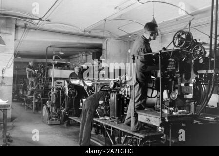 Druckereimitarbeiter bei der Arbeit an der Rotationsdruckmaschine Maschinenbaukonzerns in den Werken des MAN (Maschinenfabrik Augsburg-Nürnberg), Deutschland 1930 er Jahre. Les travailleurs de l'imprimerie sur la presse d'impression rotative dans les usines de la société d'ingénierie mécanique (homme), Maschinenfabrik Augsburg-Nürnberg Allemagne 1930. Banque D'Images