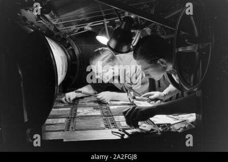 Zwei Drucker Lettern setzen zu einem von Rotationsdruckmaschine Schriftstatz un zusammen, Deutschland 1930er Jahre. Deux imprimantes sont l'organisation de type métal sortes sur une presse rotative, Allemagne 1930. Banque D'Images