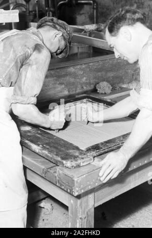 Keramiker der Staatlichen Porzellanmanufaktur bearbeiten Berlin für den Schrühbrand Keramikplatten rohe, Deutschland 1930 er Jahre. Céramistes de l'état de travail Berlin manufacture de porcelaine sur les plaques en céramique pour le tir en biscuit, Allemagne 1930. Banque D'Images