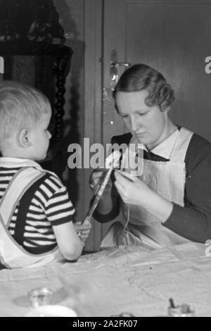 Mutter und genre beim basteln, Deutschland 1930 er Jahre. La mère et l'enfant de faire de l'artisanat, de l'Allemagne des années 1930. Banque D'Images