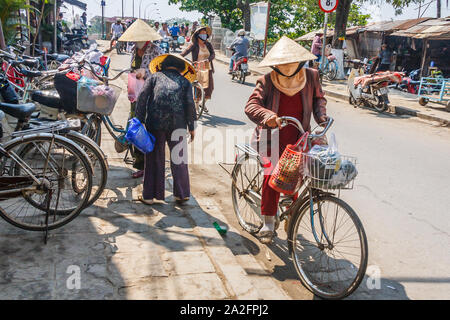 Hoi An, Vietnam - 3 mars 2010 : les femmes sur des bicyclettes. Le vélo est encore un moyen de transport populaire Banque D'Images