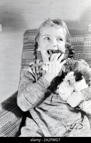 Ein Mädchen isst Liegnitzer Bomben, Deutsches Reich 1930er Jahre. Un girl eating Liegnitzer Bomben, Allemagne 1930. Banque D'Images