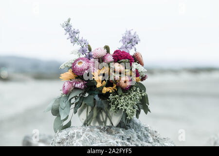 Bouquet de fleurs mixtes des branches d'eucalyptus, les mamans, et les fleurs sauvages de couleur lavande sur une pierre sur une plage à Half Moon Bay, Californie, USA Banque D'Images