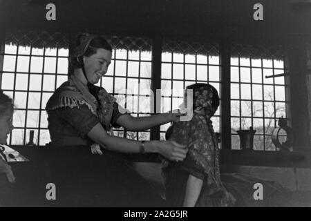 Eine Frau hilft einem kleinen Mädchen beim HANDBRAKE ! der Tracht der Gegend um Ammerland bei Bad Zwischenahn im Oldenburger Land, Deutschland 1930 er Jahre. Une femme d'aider une petite fille à porter le costume traditionnel de Ammerland près de Bad Zwischenahn au Oldenburg, Allemagne 1930. Banque D'Images