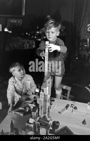 Zwei Jungen spielen am Weihnachtsabend mit den neuen Bauklötzen, Deutschland 1938. Deux garçons jouant avec la nouvelle série de blocs de jouets sous l'arbre de Noël, de l'Allemagne 1930 Banque D'Images