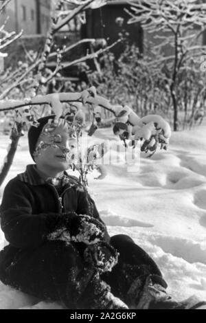 Ein kleiner Junge sitzt im Schnee, Deutschland 1930er Jahre. Un petit garçon assis dans la neige, l'Allemagne des années 1930. Banque D'Images