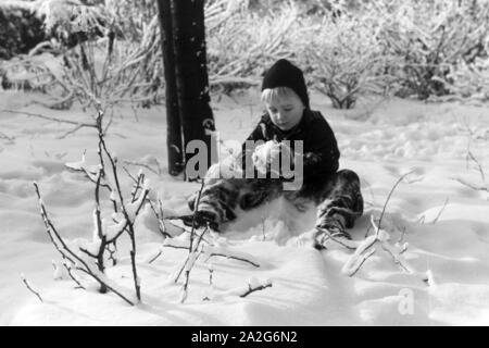 Ein kleiner Junge sitzt im Schnee, Deutschland 1930er Jahre. Un petit garçon assis dans la neige, l'Allemagne des années 1930. Banque D'Images