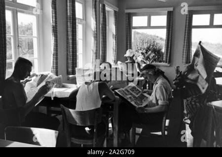 In einem Wartesaal lesen wartende les voyageurs dans die aktuellen Meldungen Haut aus der Tageszeitung, Deutschland 1930er Jahre. Les passagers en attente de lire les journaux dans une salle d'attente d'une gare principale, l'Allemagne des années 1930. Banque D'Images