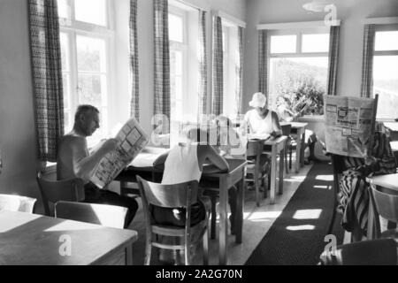 In einem Wartesaal lesen wartende les voyageurs dans die aktuellen Meldungen Haut aus der Tageszeitung, Deutschland 1930er Jahre. Les passagers en attente de lire les journaux dans une salle d'attente d'une gare principale, l'Allemagne des années 1930. Banque D'Images