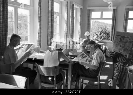 In einem Wartesaal lesen wartende les voyageurs dans die aktuellen Meldungen Haut aus der Tageszeitung, Deutschland 1930er Jahre. Les passagers en attente de lire les journaux dans une salle d'attente d'une gare principale, l'Allemagne des années 1930. Banque D'Images