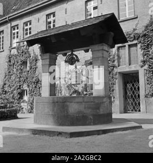 Historischer Ziehbrunnen einem Hof à Gladbach, Deutschland 1930 er Jahre. Bien dessiner historique dans une cour à Gladbach, Allemagne 1930. Banque D'Images