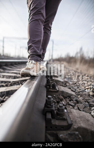 Hipster homme marche le long des rails avec confiance sur le chemin de fer. Close-up. Banque D'Images