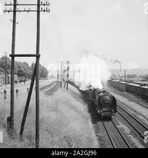 Ein Güterzug eigenschaften von einer Dampflokomotive, der Baureihe 44, durchfährt einen kleinen Bahnhof, Deutschland 1930 er Jahre. Un train de marchandises avec une locomotive à vapeur de type 44, passant d'un peu, l'Allemagne des années 1930. Banque D'Images