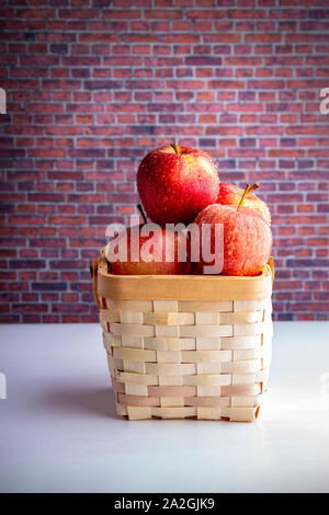 Pommes sur un panier en bois sur un tableau blanc avec un mur de briques Banque D'Images