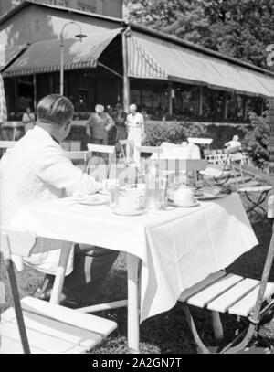 Ein Mann dans Außengastronomie sitzt der im Garten und wartet auf den Kellner, Deutschland 1930 er Jahre. Un homme assis à l'air libre gastronomie, en attente d'un serveur, l'Allemagne des années 1930. Banque D'Images