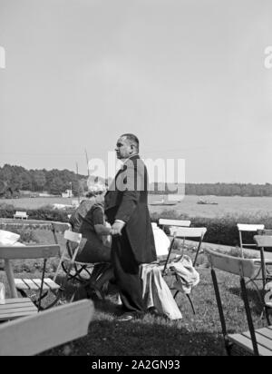 Ein Kellner im bedient fracturation eine Dame dans une Außengastronomie einem der Voir, Deutschland 1930 er Jahre. Serveur dans un manteau à queue fourchue au service d'une dame à un restaurant en plein air, de l'Allemagne des années 1930. Banque D'Images