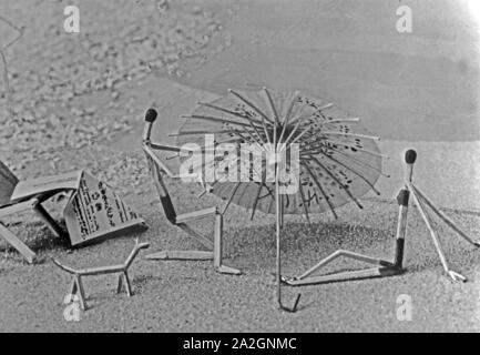 Papiermännchen-Szenerie Streichholzmännchen Pärchen : unter einem Sonnenschirm am Strand, Deutschland 1930 er Jahre. Marionnette : scénarios correspond à des gens sous un parasol à la plage, l'Allemagne des années 1930. Banque D'Images