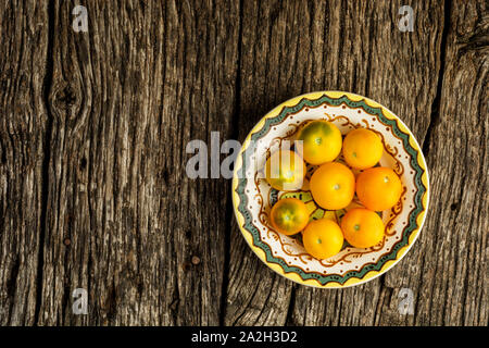 Bio frais, tomates jaune sur jaune sur la plaque de fond en bois rustique avec copie espace. Mise à plat Banque D'Images