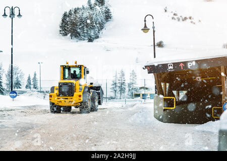 Big loader machine avec des chaînes en métal acier dépose de gros tas de neige ville rue chez alpine région de montagne en hiver. Après de fortes chutes de neige Banque D'Images