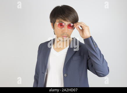 Portrait Asian Businessman en costume bleu marine rouge toucher les lunettes sur fond gris. Businessman porter en mode combinaison officielle semi st Banque D'Images