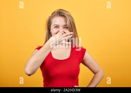 Jeune fille blonde en t-shirt rouge isolé sur fond orange montre les émotions Banque D'Images