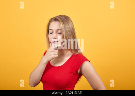 Jeune fille blonde en t-shirt rouge isolé sur fond orange montre les émotions Banque D'Images