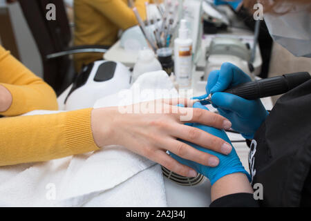 Close-up d'ongle Professionnel traitement, le meulage et le polissage avec lime à ongles électrique perceuse. Esthéticienne salon de beauté en mécanique de femmes Banque D'Images