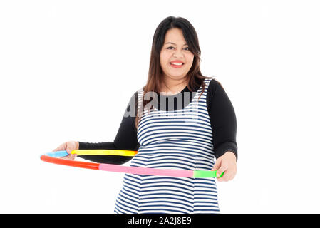 Jeune femme belle de graisse est l'exercice par hula-hoop colorés avec les deux mains. Elle sourit et aime perdre du poids pour sa bonne santé. Isolé sur un Banque D'Images