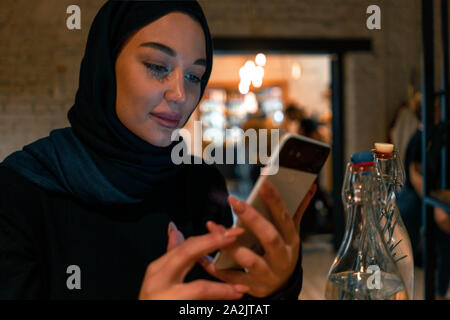 Femme musulmane dans l'aide en ligne shopping cafe téléphone mobile moderne. Concept de vivre pleinement leur vie avec l'attitude moderne contemporain de la société tolérable. Banque D'Images