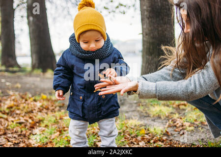 Mignon bébé garçon mode dans les tenues de explore le monde avec la mère à l'automne nature park Banque D'Images