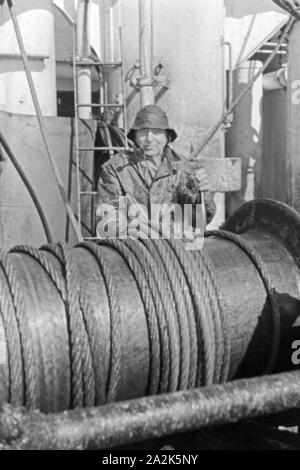 Des Fabrikschiffs Besatzungsmitglied Ein 'Jan Wellem' an der Seilwinde, 1930. Un membre de l'équipage du navire-usine 'Jan Wellem' de la flotte baleinière allemand debout au treuil, 1930. Banque D'Images