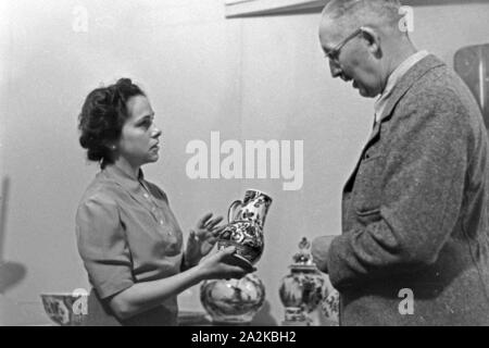 Eine Frau präsentiert auf dem Messestand feines Porzellan au der Messe Leipzig, Deutschland 1940 er Jahre. Une femme présentant la porcelaine fine sur le stand au salon de Leipzig, Allemagne 1940. Banque D'Images