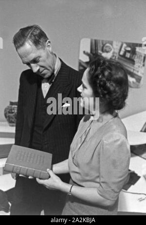 Eine Frau präsentiert ein Buch un ihre Kundschaft auf der Messe Leipzig, Deutschland 1940 er Jahre. Un greffier femelle présentant un livre, à ses clients au salon de Leipzig, Allemagne 1940. Banque D'Images