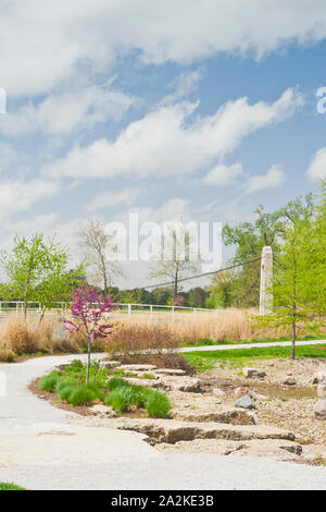 Puffy nuages flottent dans plus de redbud arbres avec des fleurs rose et le pont près du lac Post-Dispatch de rapides à St Louis Forest Park un jour de printemps. Banque D'Images