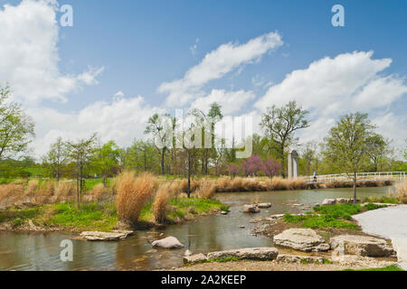 Puffy nuages flottent dans plus de redbud arbres avec des fleurs rose et le pont près du lac Post-Dispatch de rapides à St Louis Forest Park un jour de printemps. Banque D'Images