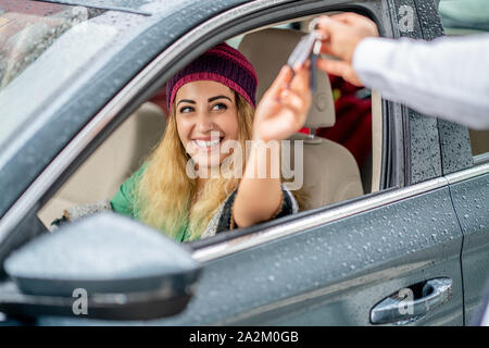 Jeune femme prendre la clé de service voiturier à conduire sa voiture. Banque D'Images